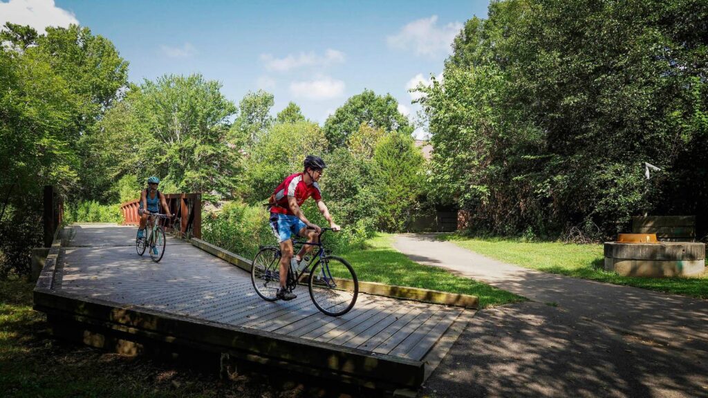 Two people cycle on a greenway trail
