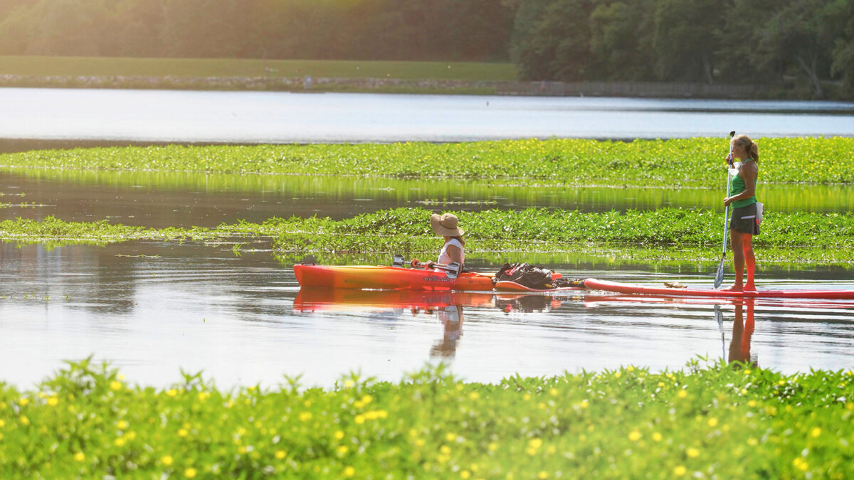 Two women kayak on the water of Lake Raleigh