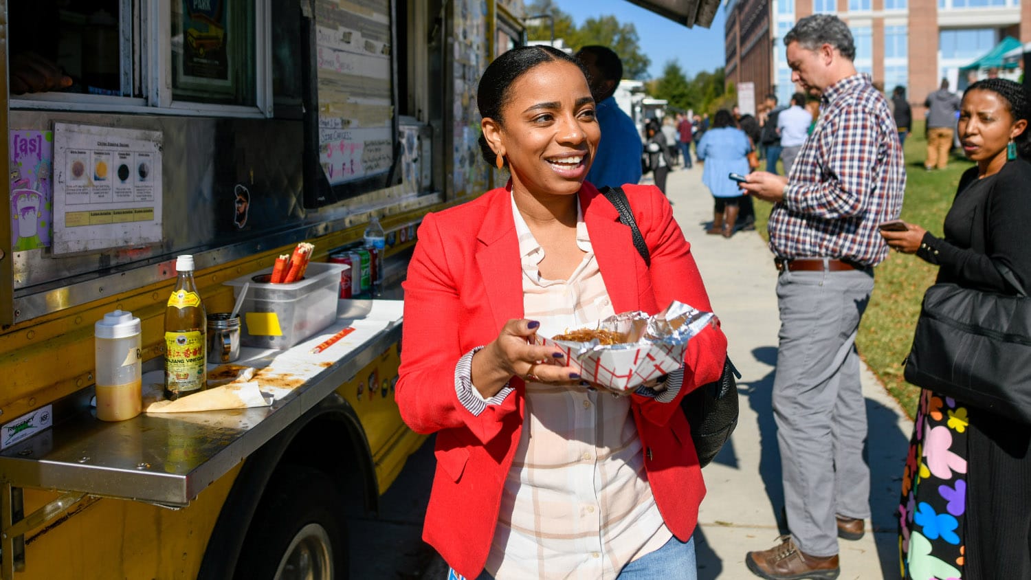 A woman smiles with a plate of food at a food truck rodea